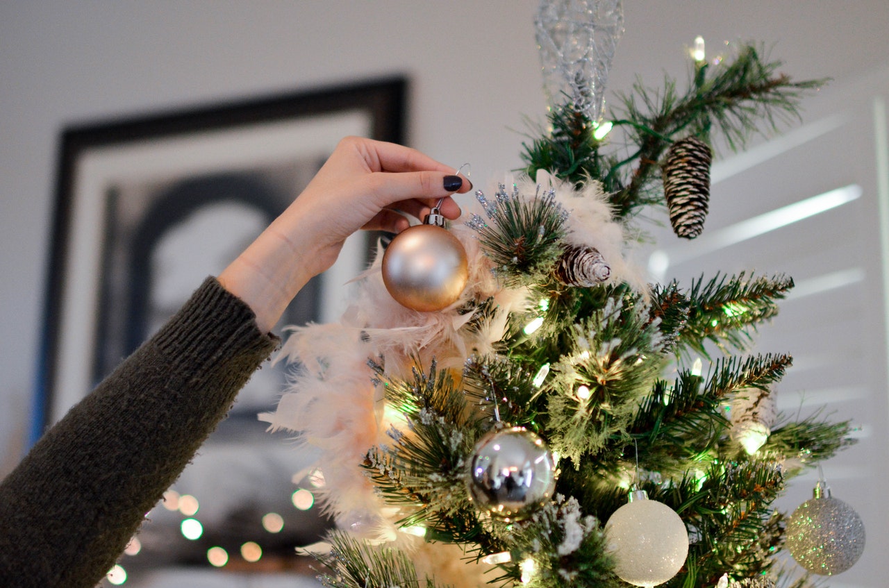 Person hænger pynt op på juletræ